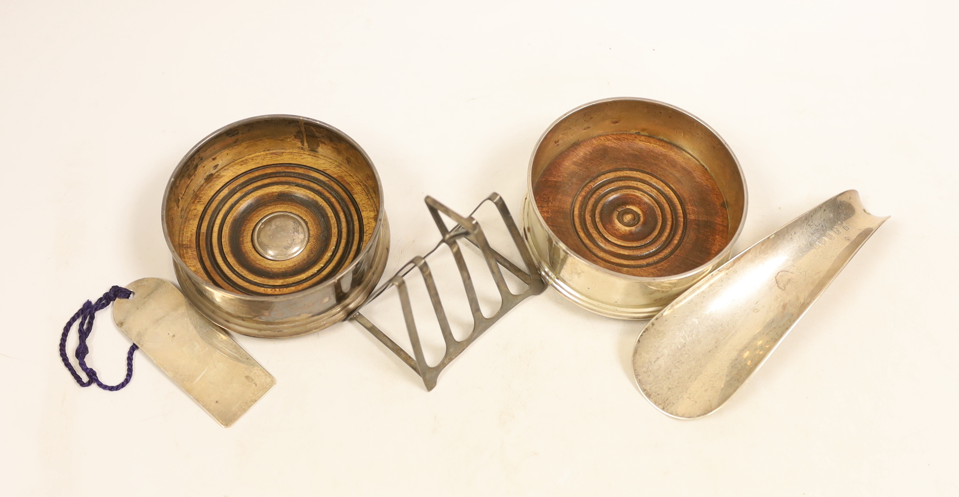 A modern pair of silver mounted wine coasters, diameter 91mm, a George V silver five bar toast rack by William Hutton & Sons, a modern silver shoehorn and a modern silver book mark.